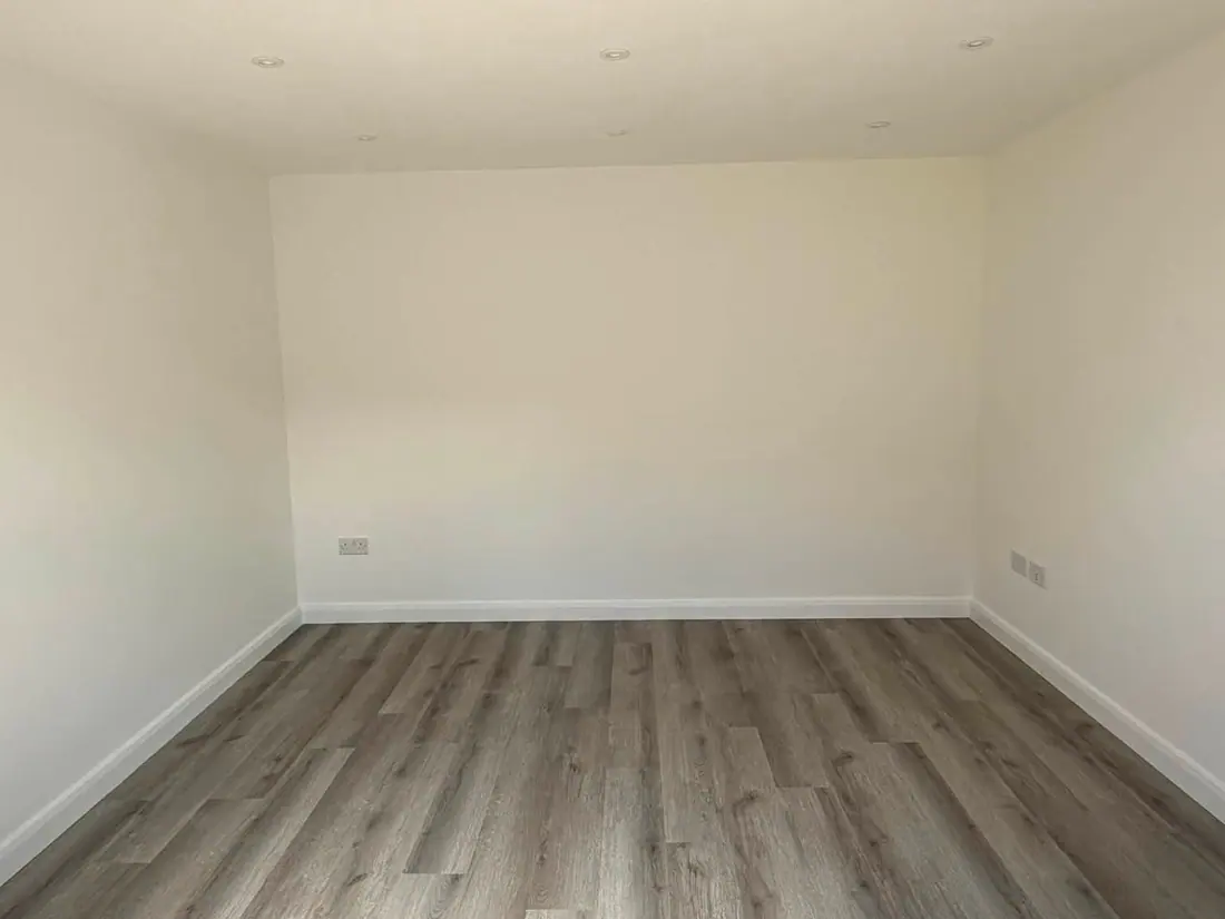A finished interior with fresh plaster, painted walls and a wood-effect floor