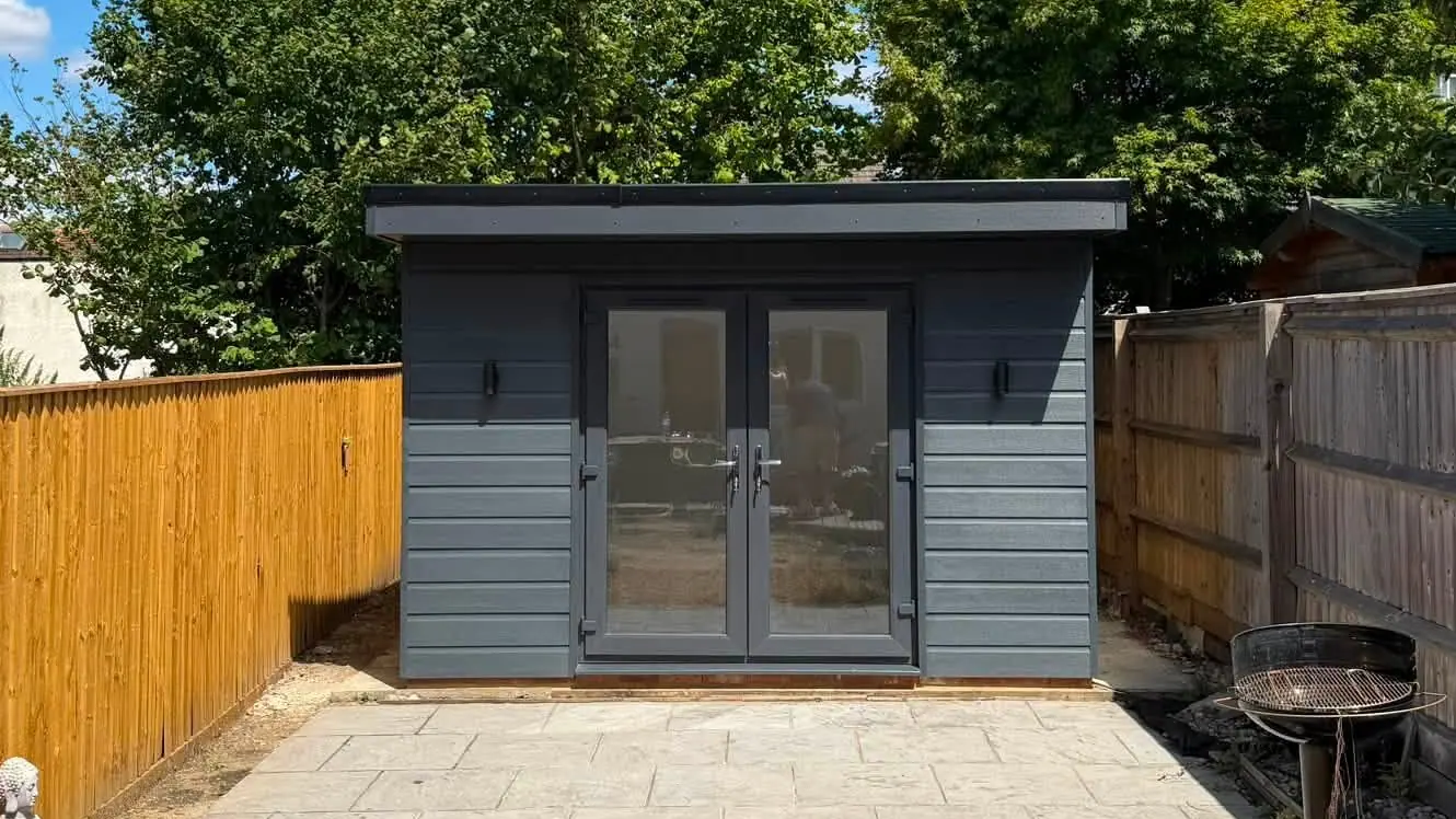 A finished grey-clad garden room with glazed double doors on a new paved patio