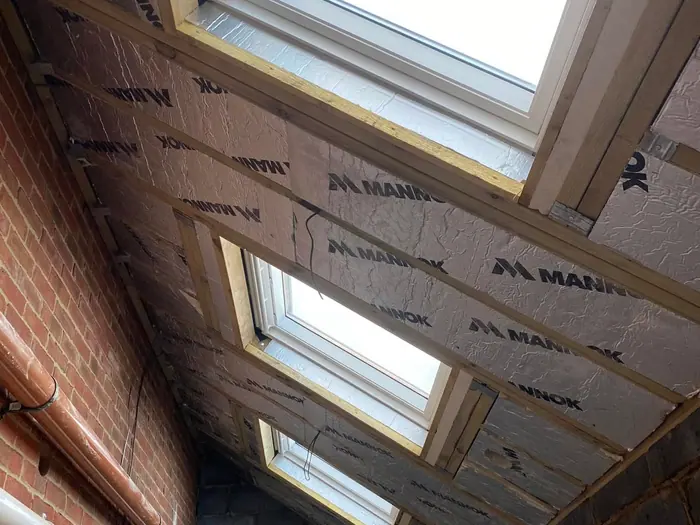 A loft conversion in progress with new Velux windows, insulation and rafters